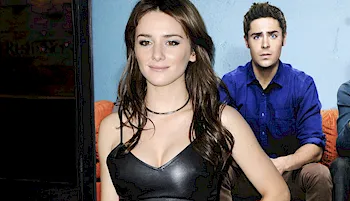 Close up of woman posing in front of a movie poster in a leather top