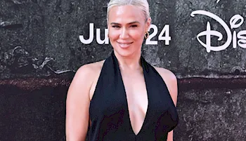 CJ Perry in a black dress and smiling on the red carpet