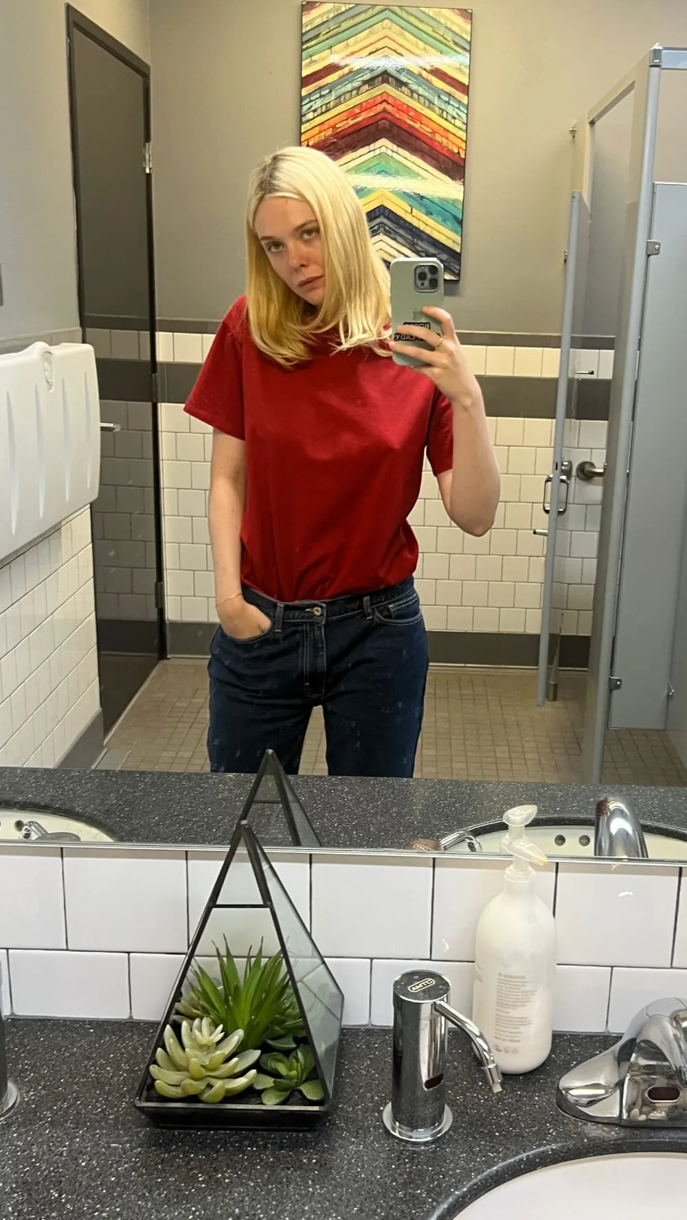 Elle Fanning braless in a red shirt snapping a selfie in the mirror