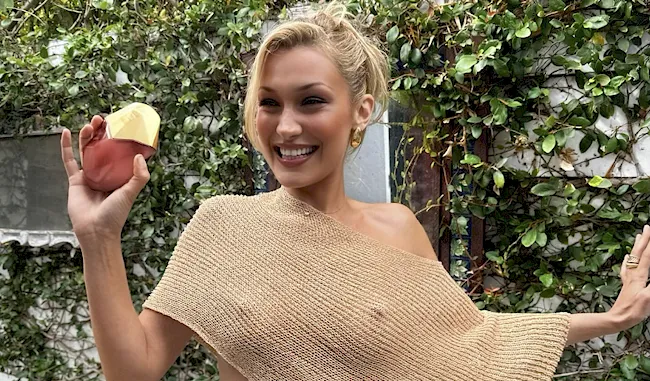 Fashion model smiles while posing braless in a slightly sheer top