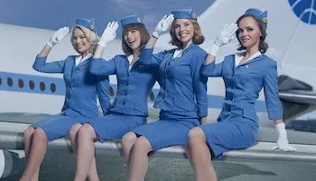Pretty Pan Am flight attendants sitting on the wing of a plane