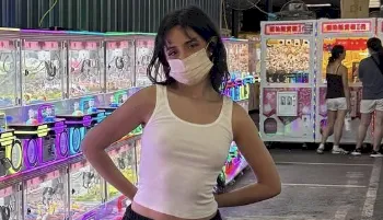 Camila Cabello wearing a tank top and face mask in an arcade