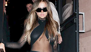 Tate McRae wearing a sexy black outfit and sunglasses while walking down a staircase