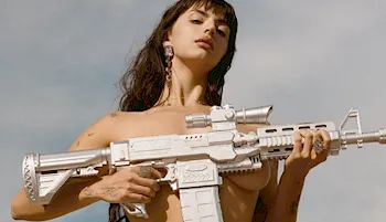 Looking up at a topless brunette holding a big space gun over her boobs