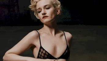 Julia Garner posing in a black and see through bra