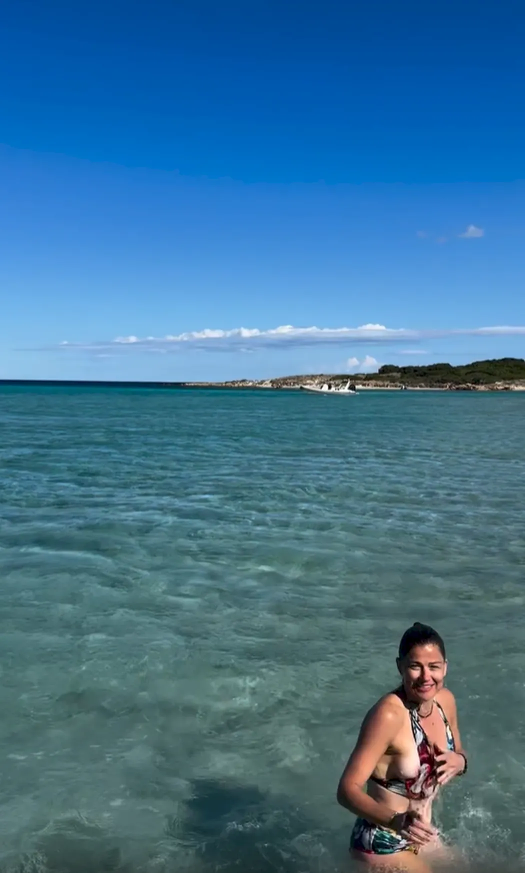 Brunette woman in a bikini standing waist deep in the water
