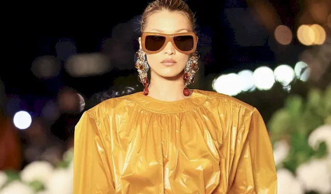 Pretty fashion model walking the runway in a yellow clear coat