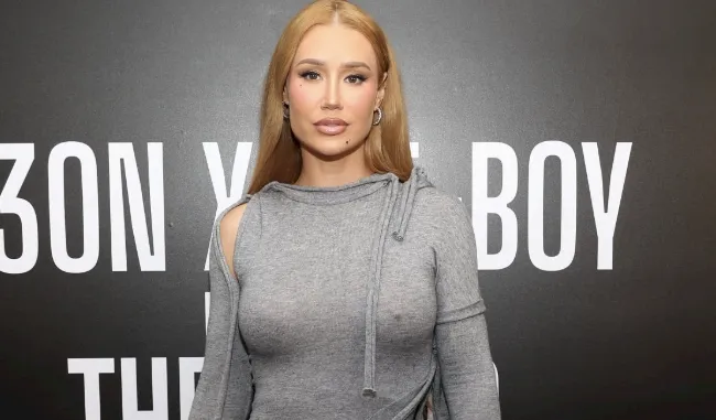Front view of Iggy Azalea braless in a tight and grey dress on the red carpet