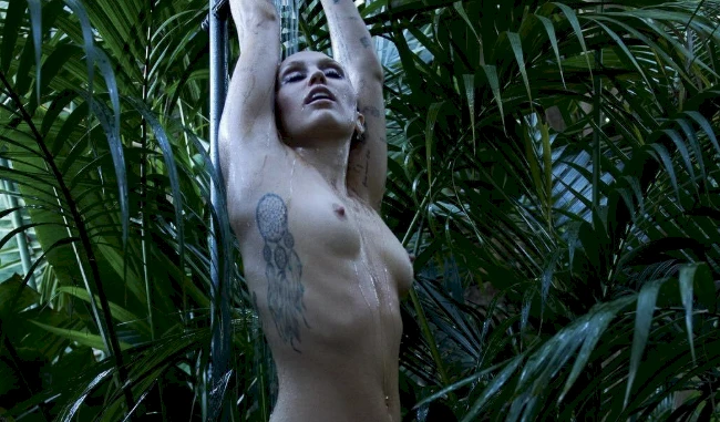 Miley Cyrus nude and wet in a shower with big leafy plants in the background