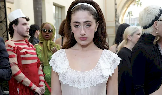 Close up of Rachel Sennott braless in a sheer dress