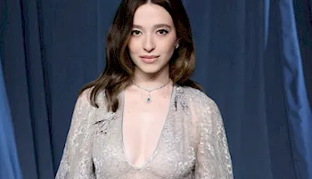 Mikey Madison from the chest up looking into the camera while wearing a semi-sheer dress