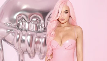 Kylie Jenner with pink hair posing in a pink dress next to big metal teeth