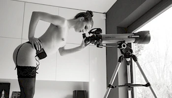 Far away side view of topless girl looking into a telescope