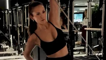 Nina Dobrev working out in the gym wearing a sports top