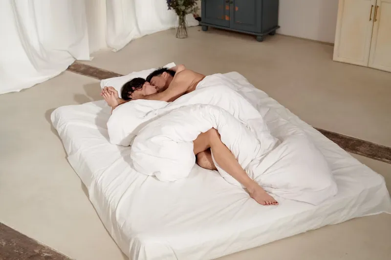 A couple snuggling among the blankets on a mattress
