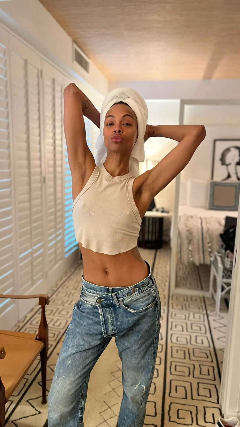 ZoeSaldanaBralessTowelH Zoe Saldana strikes a pose while braless in a white top, wearing jeans and a towel on her head