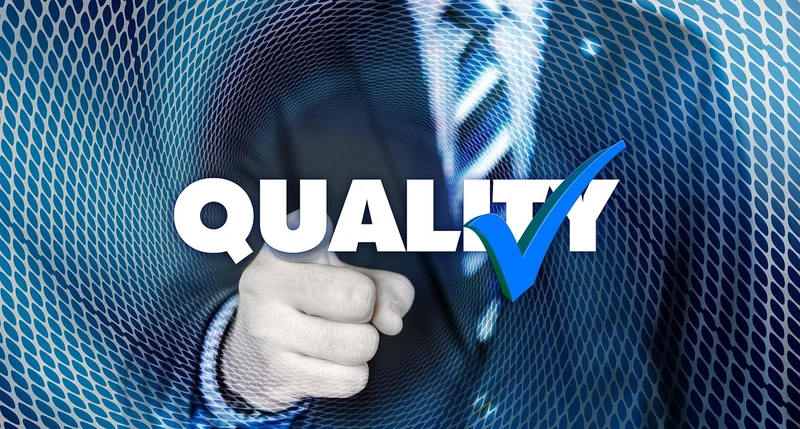 Close up of man in a suit pointing towards camera with the word QUALITY written