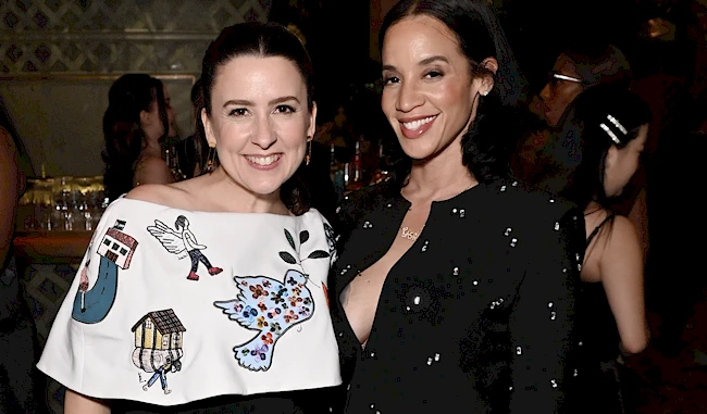 Two ladies smiling while posing for the camera at a party