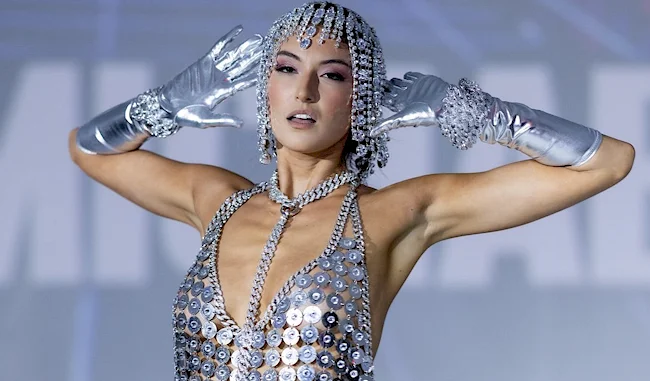 Close up of woman holding her hands behind her head wearing a metallic dress and head dress