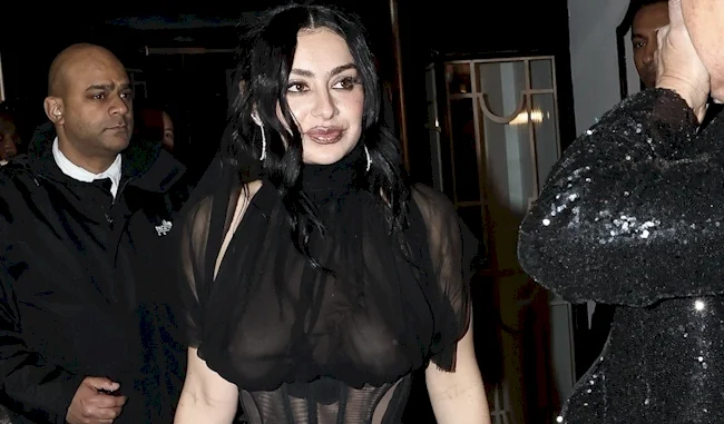 Candid close up of Charli XCX wearing a sheer black dress while looking to her side