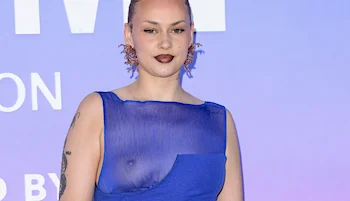 Cropped version of a woman wearing a sheer dress revealing one her breasts on the red carpet