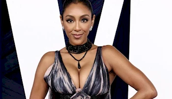 Close up of a black woman with big breasts posing in front of a camera