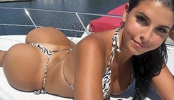 Girl look into the camera while laying on her stomach in a bikini