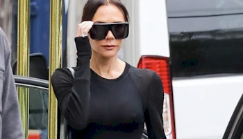 Cropped view of a woman adjusting her sunglasses while out on a public sidewalk