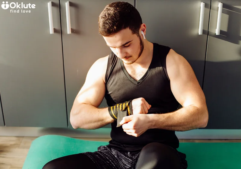 Frontal of fit man sitting down and wrapping his wrist with tape