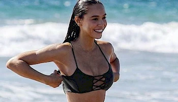 Close up of wet and smiling girl adjusting her bikini top