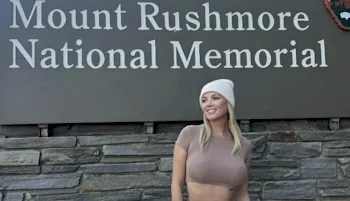 Smiling girl posing in front of a big sign that reads "Mount Rushmore National Memorial"