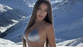 Close up of a woman on her side in a bikini top with snow in the background