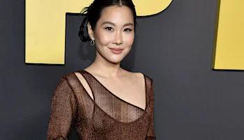 Asian actress smiles while posing at a red carpet premiere