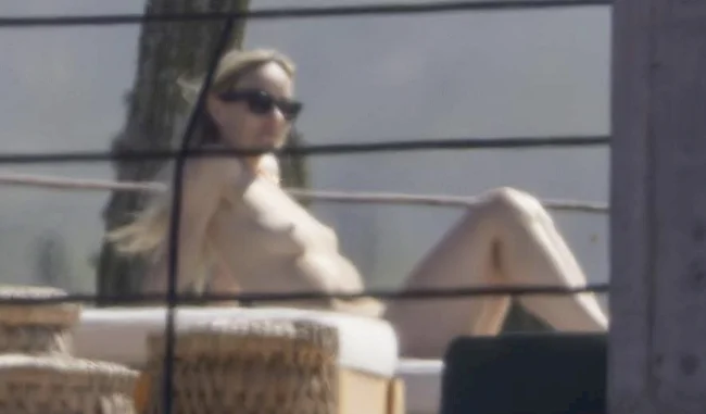 Far away view of a topless woman leaning back in a sunchair