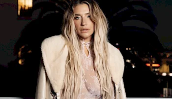 Close up of Kesha wearing a lace dress and coat