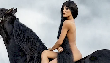 Side view of nude woman sitting on the back of a horse