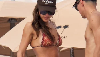 A woman in a bikini at the beach standing next to a man