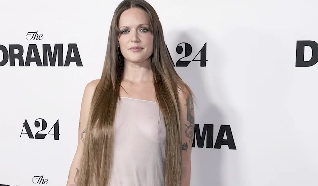 A woman with long hair wearing sheer white dress at event