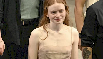 A redhead girl smiling while standing on a stage among other people