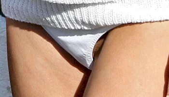 Close up of a woman's crotch wearing a white bikini bottom. A hint of her labia is showing.