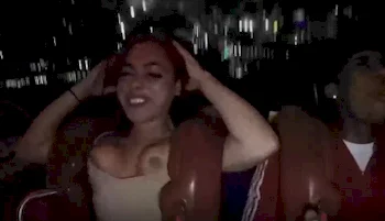 A girl's breasts falling out of her top while she is riding an amusement ride.