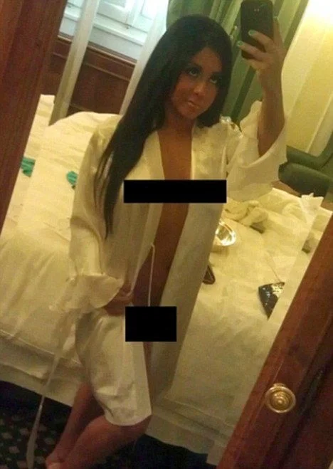 A woman takes a selfie wearing an open pajamas. She is holding her phone up and black bars cover her breasts and crotch.