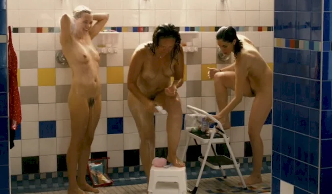 Three nude and wet women soaping themselves in a shower.