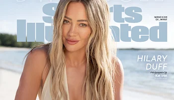 Hilary Duff poses on a sandy beach in front of the ocean, wearing a light-colored swimsuit for the Sports Illustrated cover. The magazine’s logo and her name appear in large text behind her.