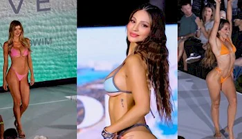 Three women model brightly colored bikinis on a fashion runway, posing confidently. The background shows an audience watching the show and a screen displaying visuals.