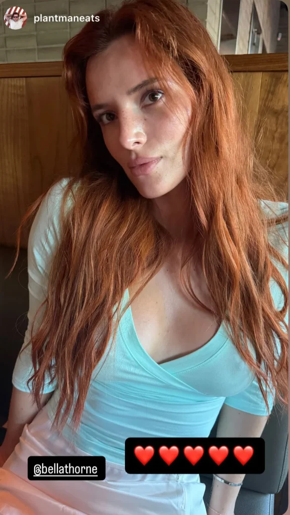 A woman with long red hair wearing a light blue top sits indoors, looking at the camera. There are heart emojis and Instagram handles @plantmaneats and @bellathorne on the image.