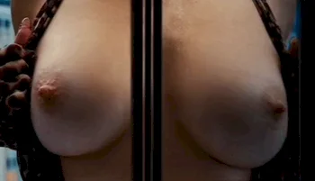 Close up of giant bare breasts behind a window.