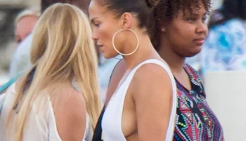 Jennifer Lopez walking by in a tank top. Two other women are in the background.