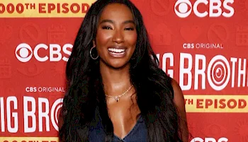 A woman with long dark hair smiles in front of a red backdrop with CBS and Big Brother 25th Episode logos.