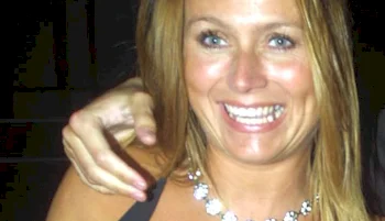 Close up of smiling blonde woman's face. A hand appears over her shoulder.